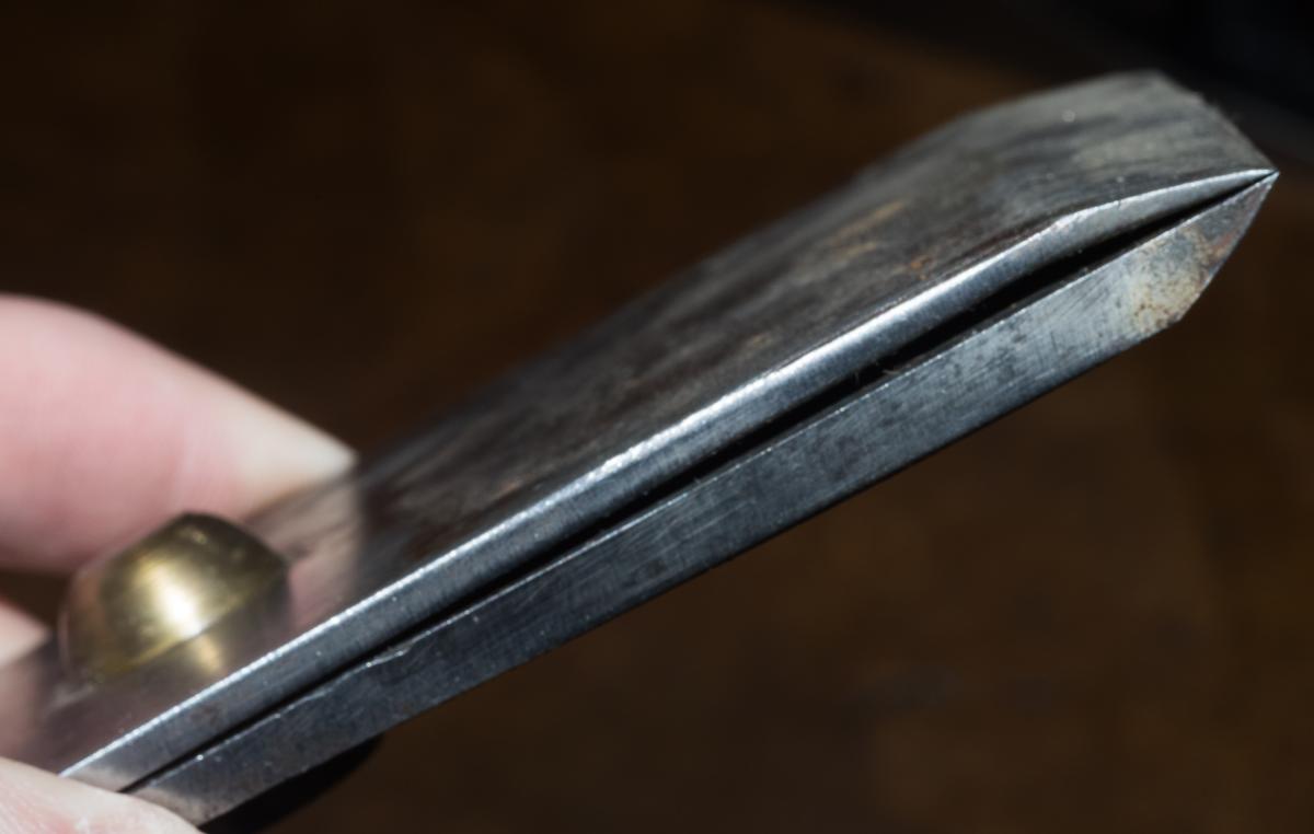 This cap iron probably mid-19th century comes out of a much earlier jointer plane by Christopher Gabriel. Tapping steel without a good machine shop is tricky so it was pretty common to instead solder in a brass nut to the cap iron